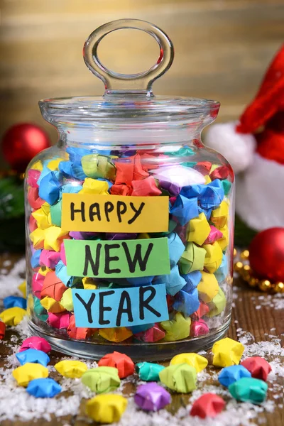 Paper stars with dreams in jar on table on wooden background — Stock Photo, Image