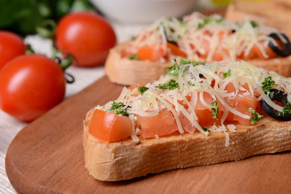 Deliciosa bruschetta con tomates en la tabla de cortar de cerca — Foto de Stock