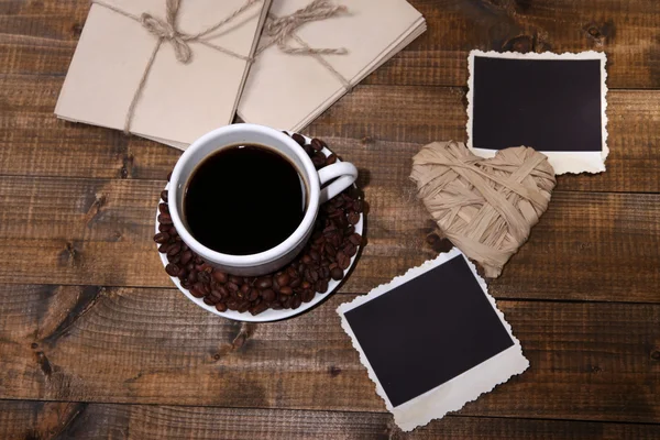 Koffiekopje en oude foto's in het lege, op houten achtergrond — Stockfoto