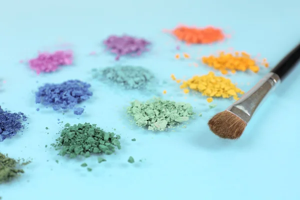 Rainbow crushed eyeshadow and professional make-up brush on blue background — Stock Photo, Image