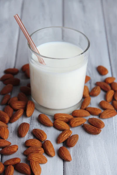 Leche de almendras en vaso con almendras en tazón, sobre fondo de madera de color —  Fotos de Stock