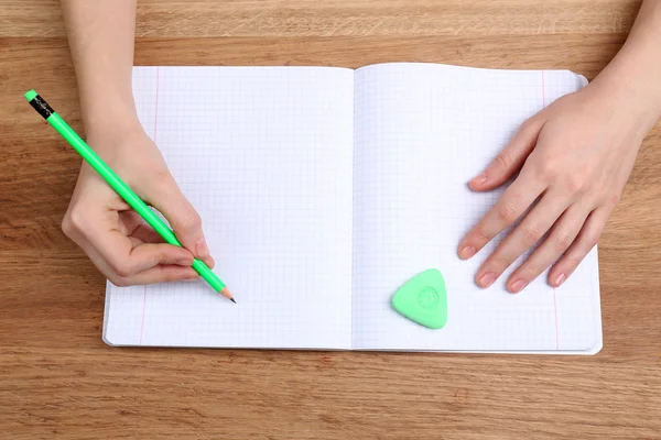 Menselijke handen met potlood schrijven op papier en wissen rubber op houten tafel achtergrond — Stockfoto