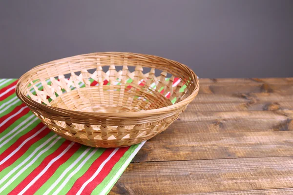 Empty wicker basket on wooden table, on dark background — Stock Photo, Image