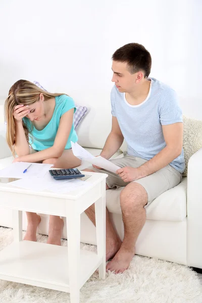 Young couple calculating finance at desk, on home interior background — Stock Photo, Image