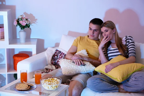 Junges Paar schaut bei Verdunkelung zu Hause fern — Stockfoto