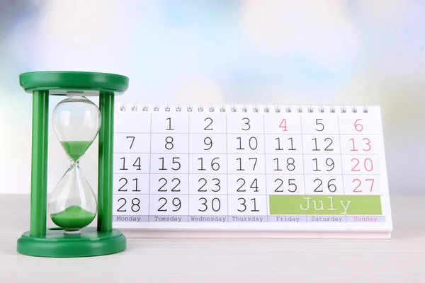 Hourglass and calendar on bright background — Stock Photo, Image