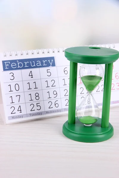 Hourglass and calendar on bright background — Stock Photo, Image