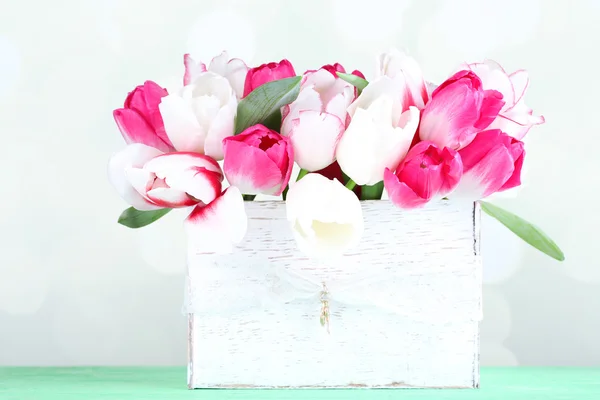 Mooie tulpen in houten doos, op lichte achtergrond — Stockfoto