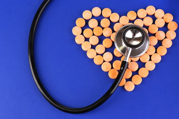 Сердце таблетки и стетоскоп на голубом фоне — стоковое фото