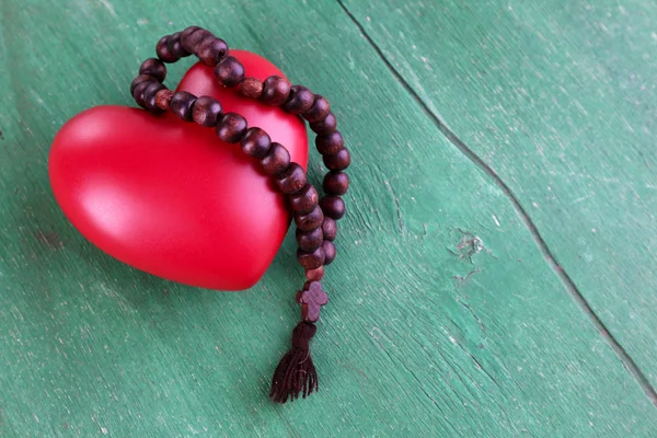 Cuore con rosario su sfondo di legno — Foto Stock