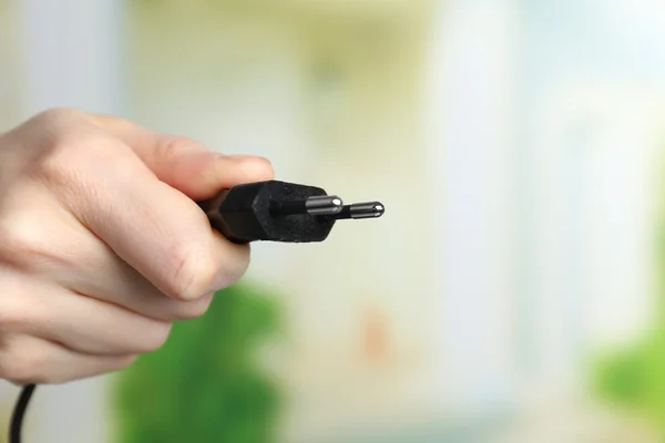 Hand som håller elektrisk kontakt på natur bakgrund — Stockfoto