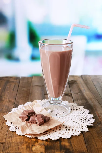 Leite de chocolate em vidro, na mesa de madeira, no fundo brilhante — Fotografia de Stock