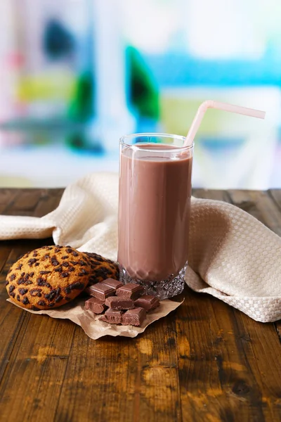 Chocolate milk in glass, on wooden table, on bright background — Stock Photo, Image