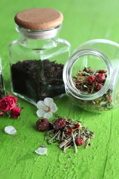 Surtido de hierbas y té en frascos de vidrio sobre fondo de madera — Foto de Stock