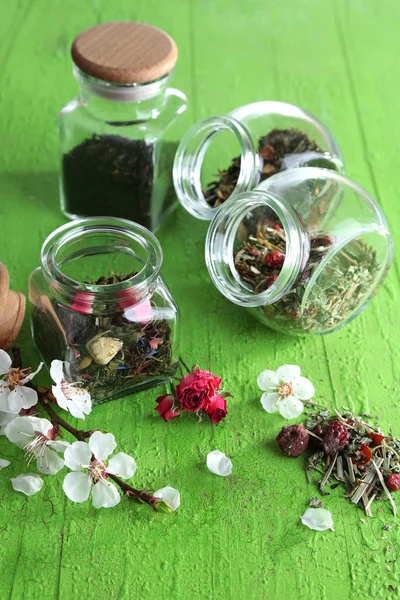 各式各样的草药和茶玻璃罐木制背景 — 图库照片