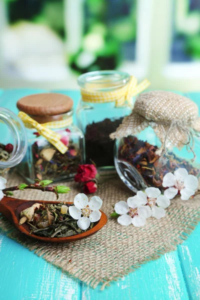 Bylinky a čaje ve sklenicích na dřevěný stůl, na světlé pozadí — Stock fotografie