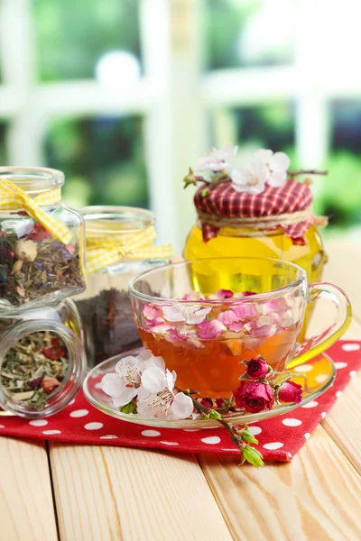 Surtido de hierbas, miel y té en frascos de vidrio sobre mesa de madera, sobre fondo brillante —  Fotos de Stock