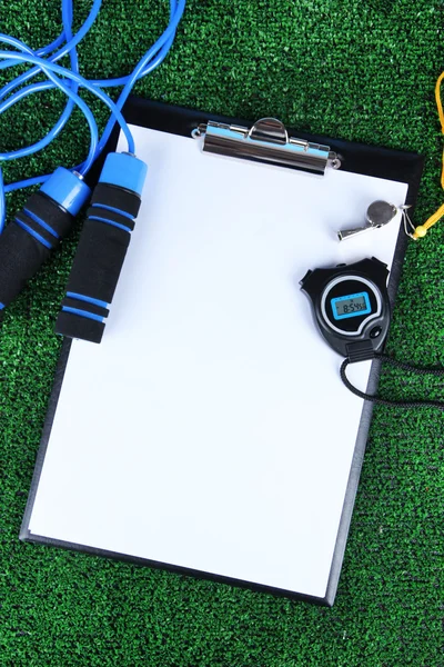Sheet of paper and sports equipment on grass close-up — Stock Photo, Image