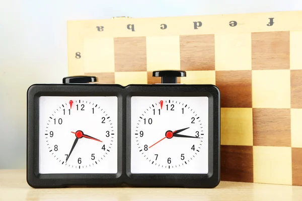 Chess clock and board on light background