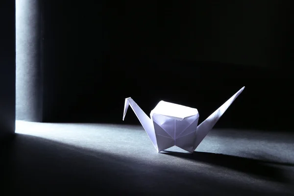 Origami kraan op donkere achtergrond met licht — Stockfoto