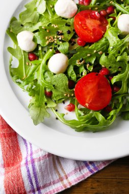 roka, domates, peynir mozzarella toplar ve ahşap zemin üzerinde plaka üzerinde susam ile yapılan yeşil salata