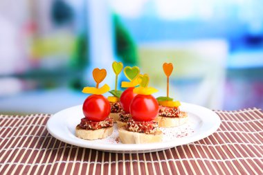 leziz kanepeler ile salam, domates, biber, fesleğen yaprakları, plaka üzerinde açık renkli ahşap tablo