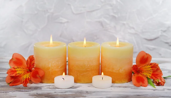 Lindas velas com flores na mesa em fundo cinza — Fotografia de Stock