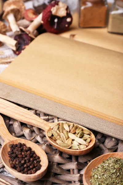 Different spices and cook book on wooden table, close up — Stock Photo, Image