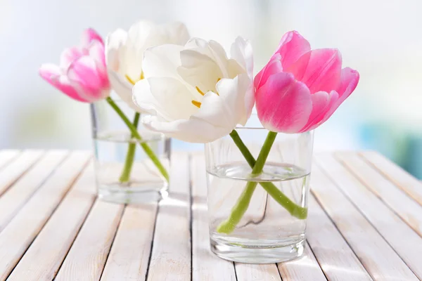 Vackra tulpaner i hink i vas på bordet på ljus bakgrund — Stockfoto