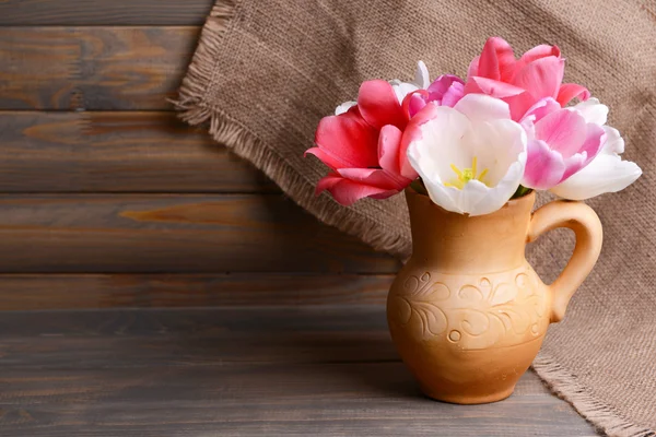 Beautiful tulips in bucket in pitcher on table on grey background — Stock Photo, Image