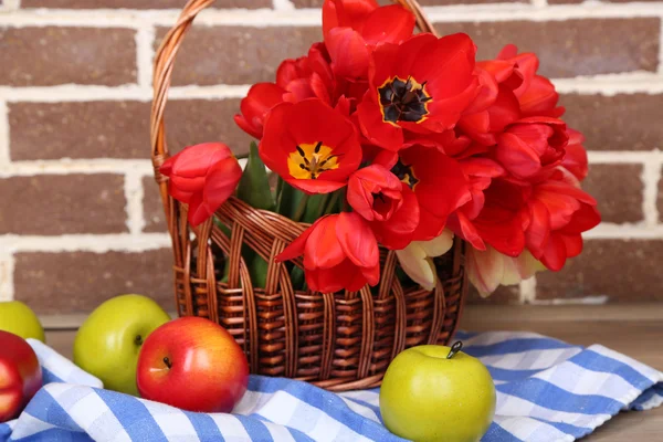 Kytice barevné tulipány v proutěném koši, na světlé pozadí — Stock fotografie