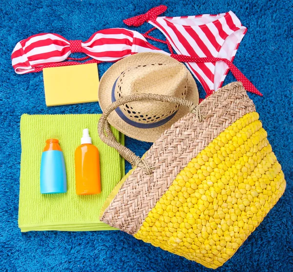 Wicker bag, swimsuit, bottles with lotions on color background. — Stock Photo, Image