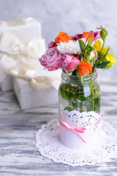 Piękny bukiet kwiatów jasny w słoiku na stole na szarym tle — Zdjęcie stockowe