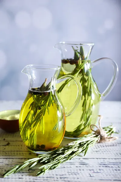 Esenciální olej s rosemary ve skleněné konvici, na světlé pozadí — Stock fotografie