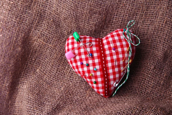Corazón de tela con alfileres de color sobre fondo de saco —  Fotos de Stock