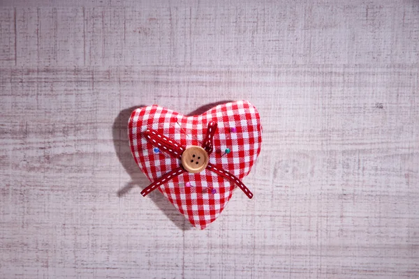 Fabric heart with color  pins on wooden background Royalty Free Stock Images