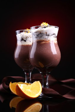 koyu renk arka plan üzerinde çikolata, krema ve portakal soslu lezzetli tatlı