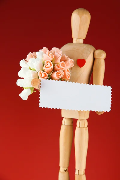 赤の背景の空白のラベルと花束を保持している木製のマネキン — ストック写真