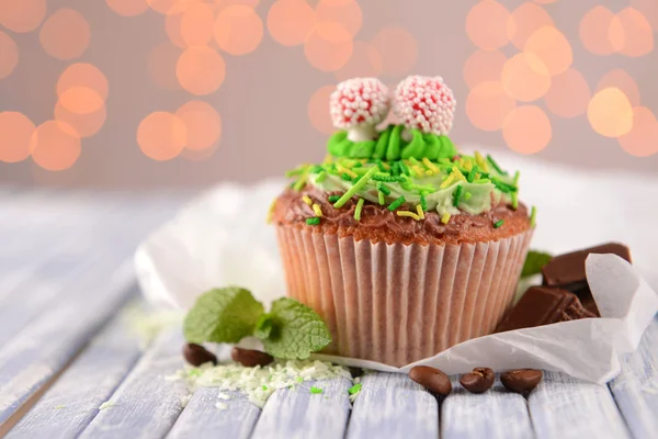 Sabroso cupcake con crema de mantequilla, sobre tabla de madera de color, sobre fondo de luces — Foto de Stock