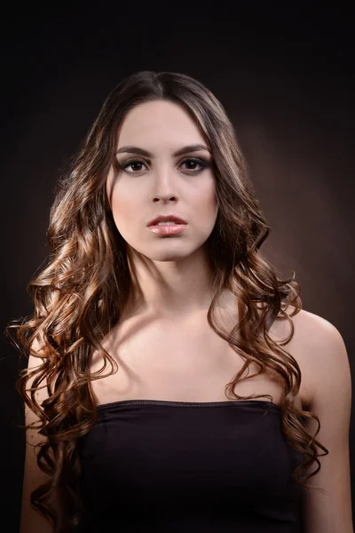 長い髪の暗い茶色の背景に美しい若い女性 — ストック写真