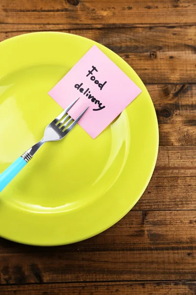 Nota carta con messaggio attaccato alla forchetta, su piatto, su sfondo di legno a colori — Foto Stock