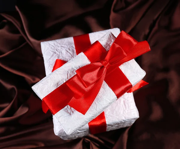 Hermosos regalos con cintas rojas sobre fondo de seda — Foto de Stock