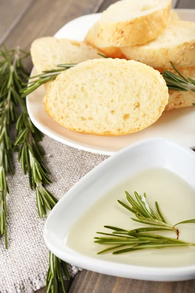 Fresh bread with olive oil and rosemary on wooden table — Stock Photo, Image