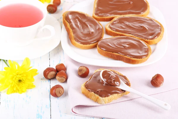 Pão com avelã de chocolate doce espalhado na placa na mesa — Fotografia de Stock