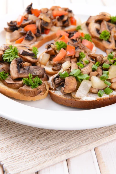 Delicious bruschetta with mushrooms on plate on table close-up — Stock Photo, Image