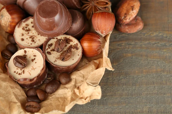 美味的巧克力糖果，与咖啡豆和木制的背景上的螺母 — 图库照片