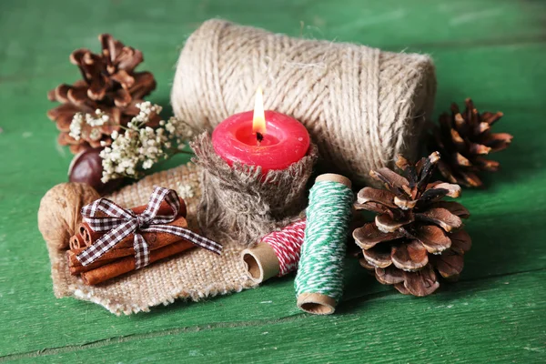 Composição com colisão natural, vela, linha, paus de canela no fundo de madeira — Fotografia de Stock