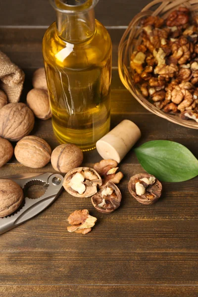 Olej z vlašských ořechů a ořechy na dřevěný stůl — Stock fotografie