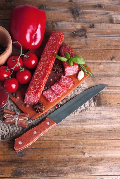 Tasty salami sausage and spices on wooden background — Stock Photo, Image