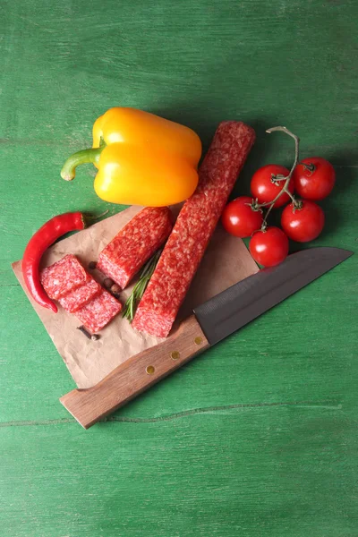 Kiełbasa salami smaczny, warzywa i przyprawy na tło drewniane — Zdjęcie stockowe